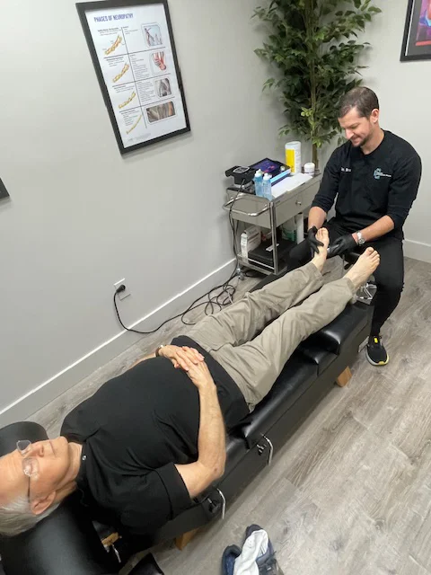 Dr. Bran Chinn performing shockwave therapy on a foot while the patient relaxes