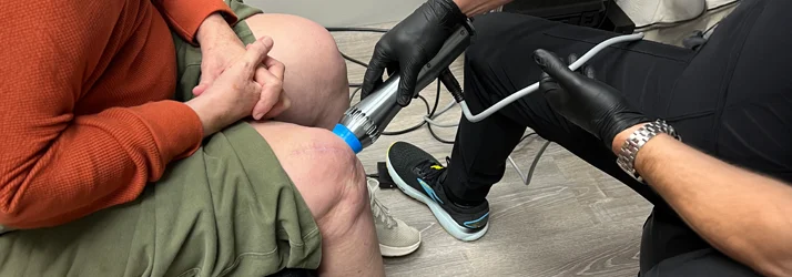 A patient receiving shockwave therapy on their knee